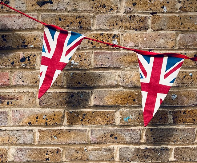 Union Jack bunting against a brick wall, red white and blue